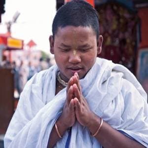 A young monk with palms joined in prayer