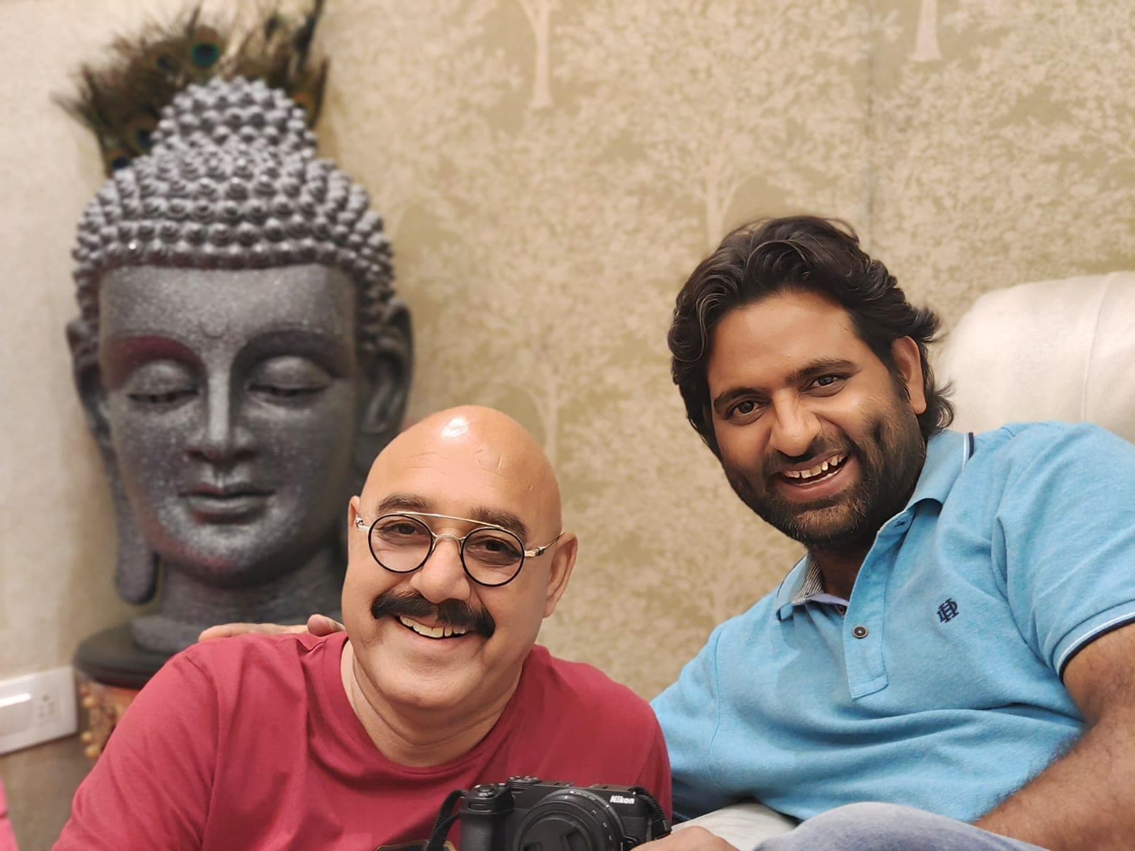 Dr. D.P. Shukla with a visitor beside a stone Buddha head