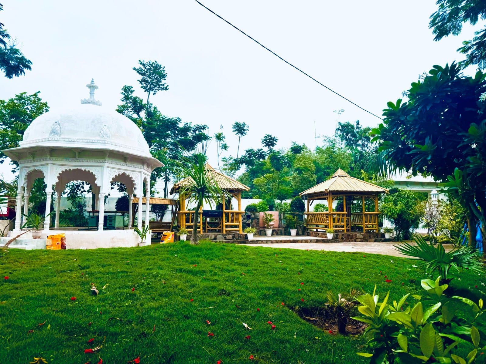 A white gazebo and thatched huts across the lawns of Anantpuram