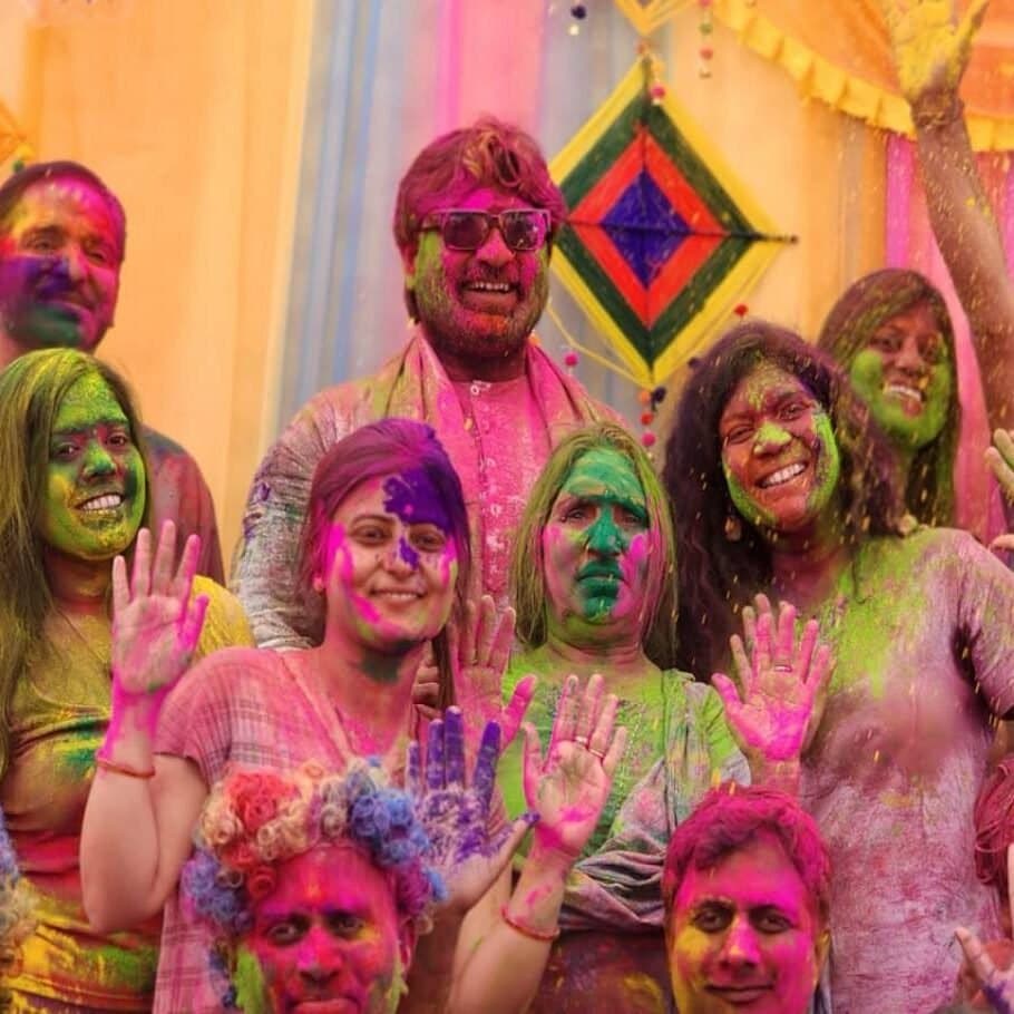 Friends covered in Holi colours, laughing together at an Anant Parivar celebration