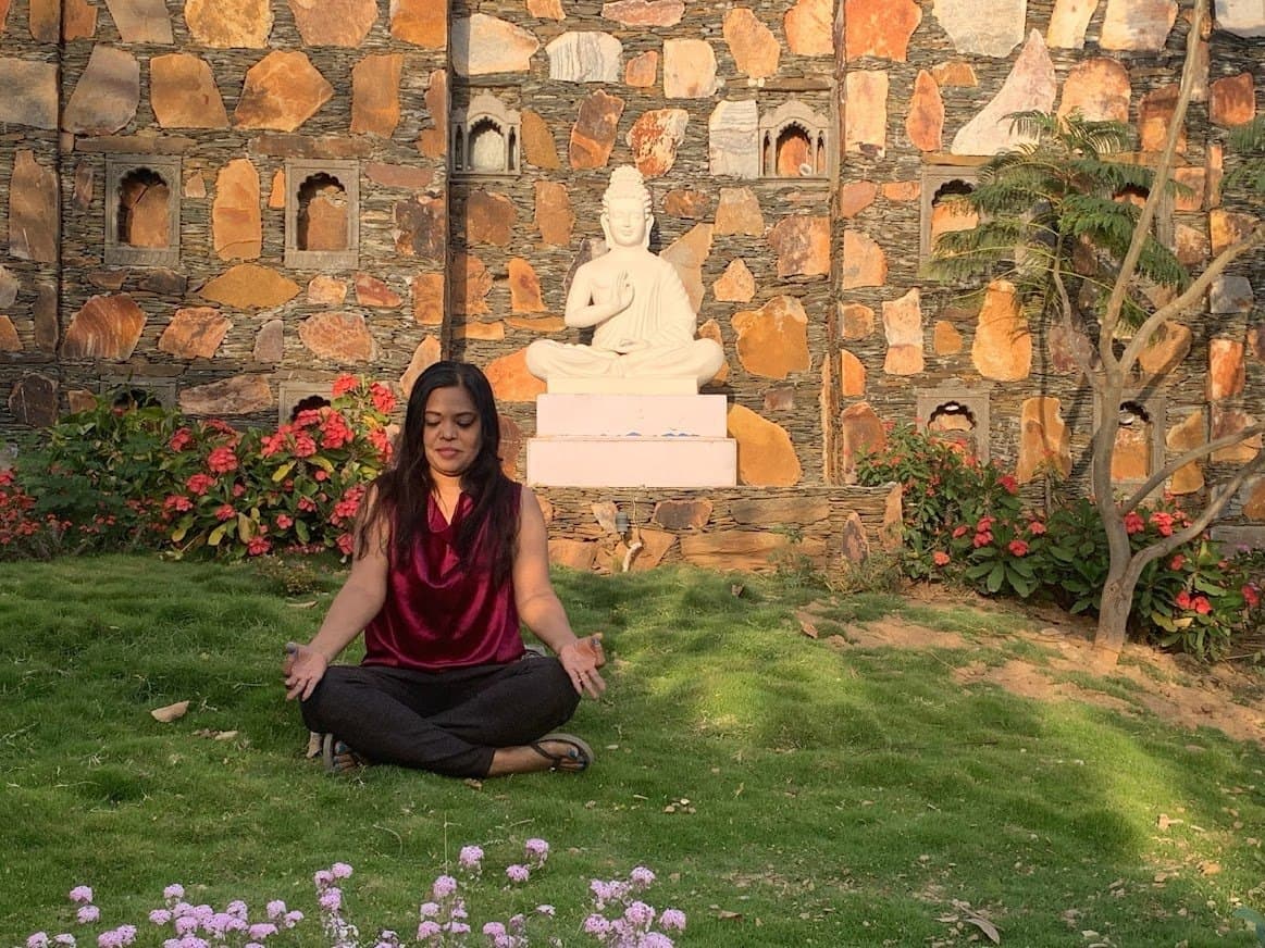 A visitor meditating on the lawn at Anantpuram
