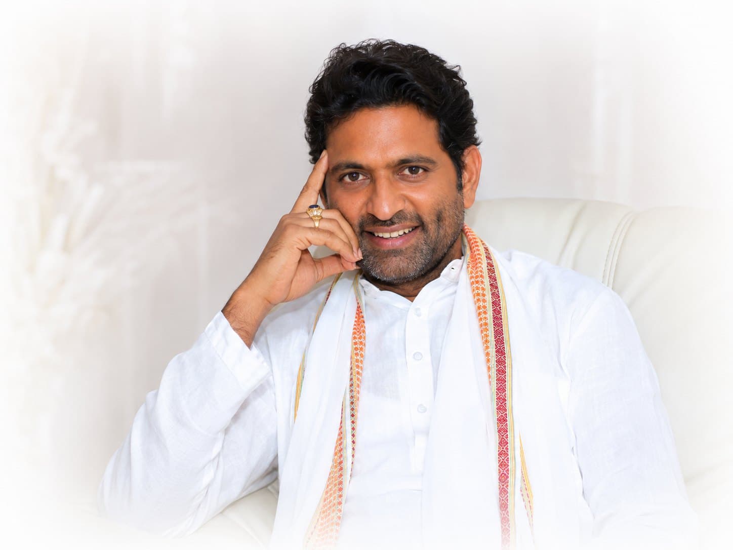 Portrait of Dr. D.P. Shukla in white, smiling, one hand raised to his temple
