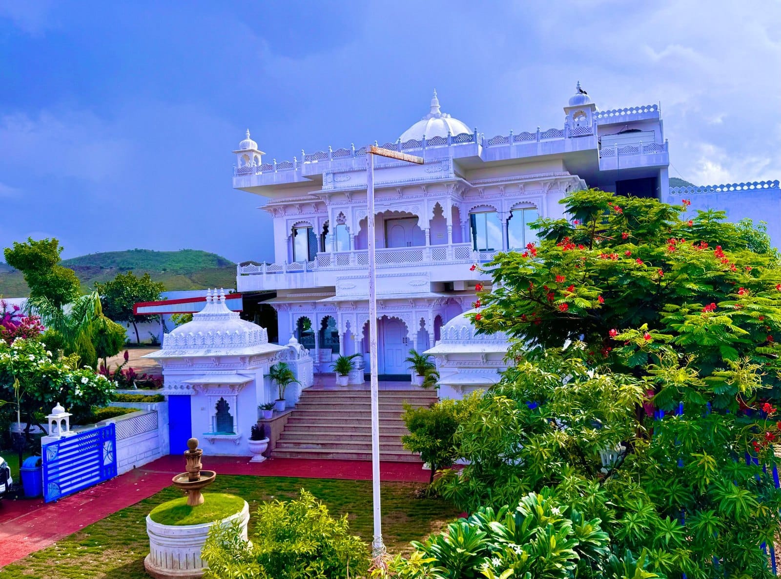 Anantpuram's white main building with domes and steps, framed by flowering trees